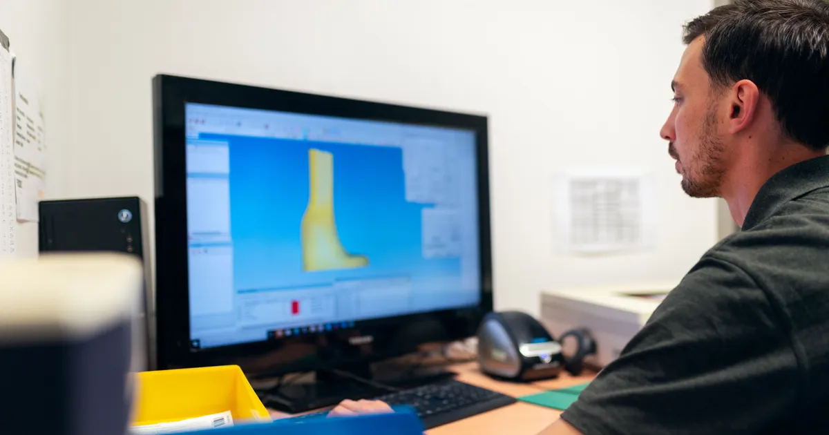 Ingeniero revisa el modelo 3D de una pieza en un programa de CAD en el monitor de su escritorio