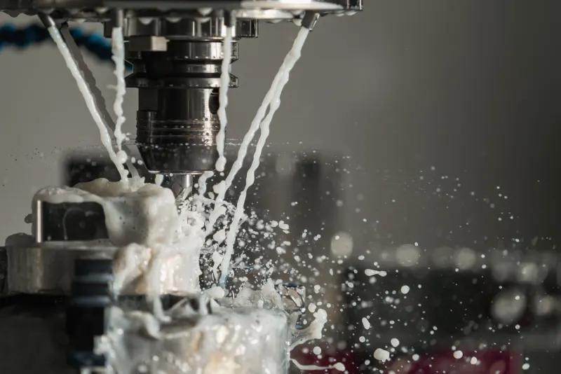 Husillo de una fresadora CNC cortando metal con chorro de refrigerante