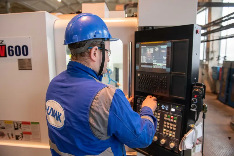 Operario programando el panel de control de un torno CNC